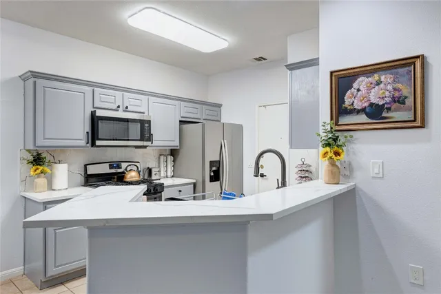 a kitchen with stainless steel appliances a sink a microwave a refrigerator and a microwave