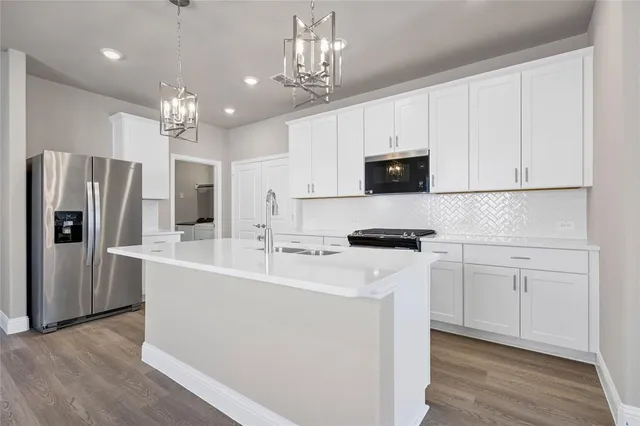 a kitchen with stainless steel appliances granite countertop a refrigerator a sink dishwasher a stove top oven a refrigerator and white cabinets