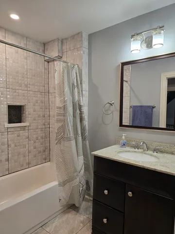 a bathroom with a sink vanity mirror and bathtub