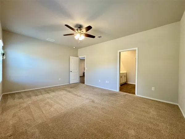 a view of an empty room and chandelier fan
