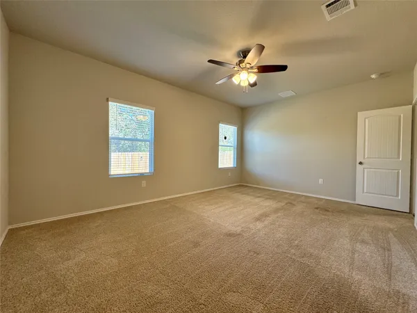 an empty room with windows and fan