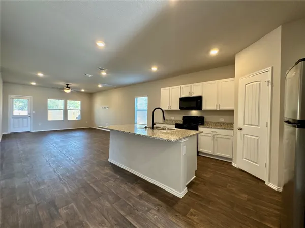 a kitchen with stainless steel appliances granite countertop a refrigerator sink and white cabinets
