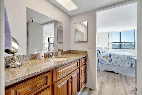 a bathroom with a granite countertop sink two mirror and shower
