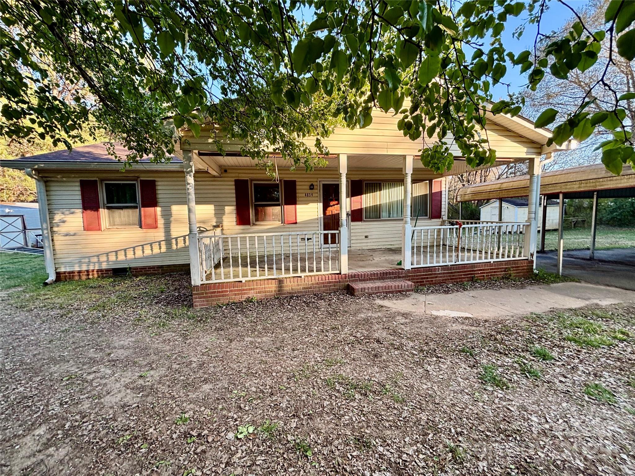 a view of a house with a small yard and a large tree