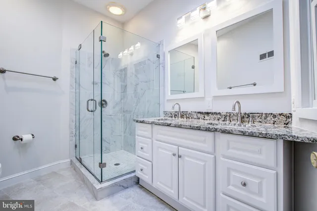 a bathroom with a granite countertop sink a mirror and a shower