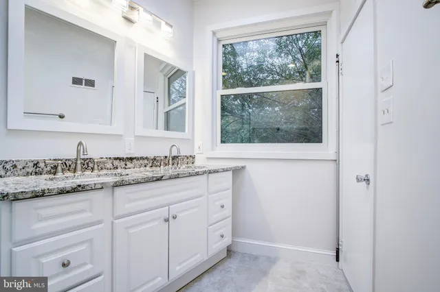 a bathroom with a granite countertop sink mirror and a window