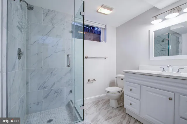 a bathroom with a granite countertop sink a toilet and a shower