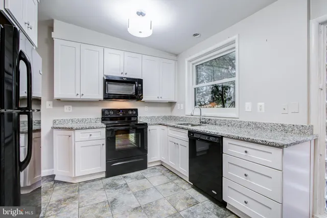 a kitchen with granite countertop a stove sink and microwave