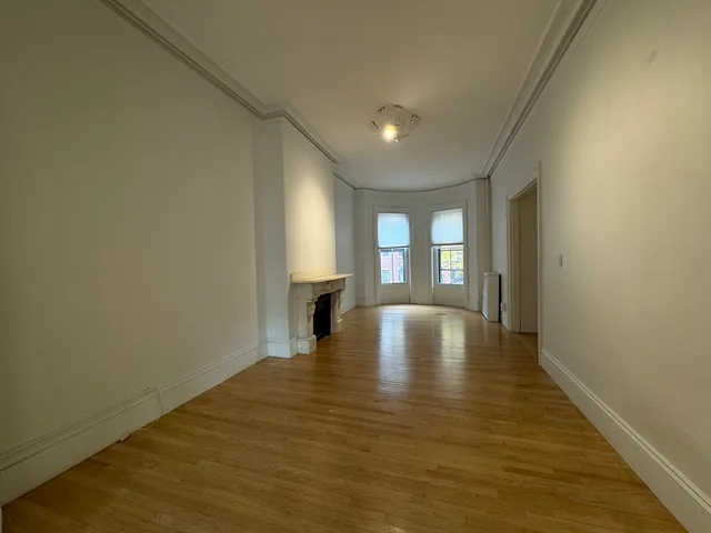 a view of empty room with wooden floor and window
