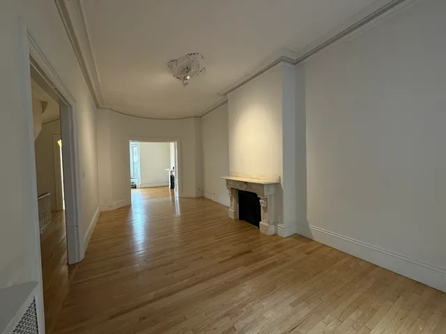 a view of empty room with wooden floor and fireplace