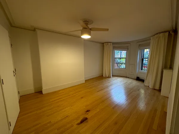 an empty room with wooden floor and windows