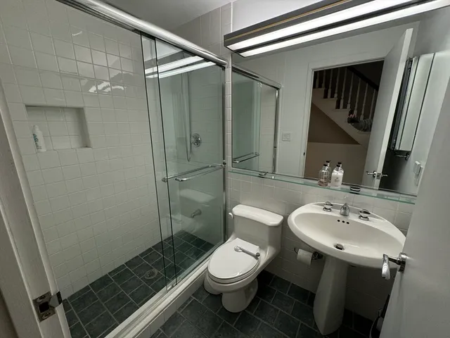 a bathroom with a sink a toilet a mirror and shower