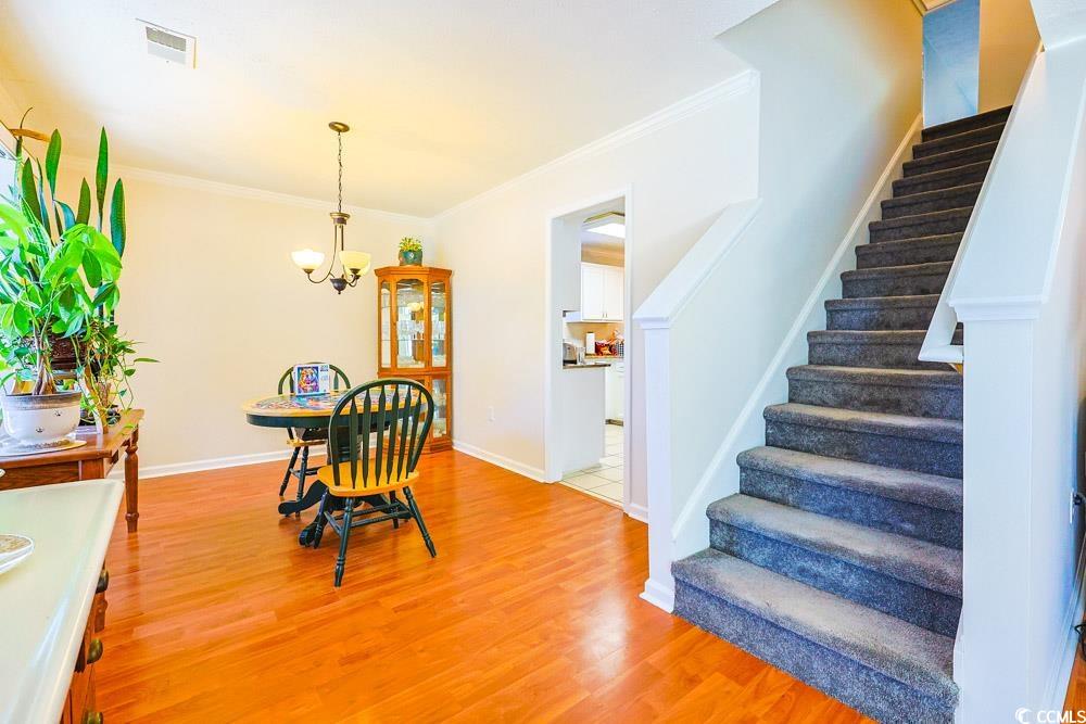 2033 Chadbury Lane Myrtle Beach, SC 29588 - Photo 12 of 39 Dining space featuring crown molding, light wood-style flooring, a chandelier, and stairway