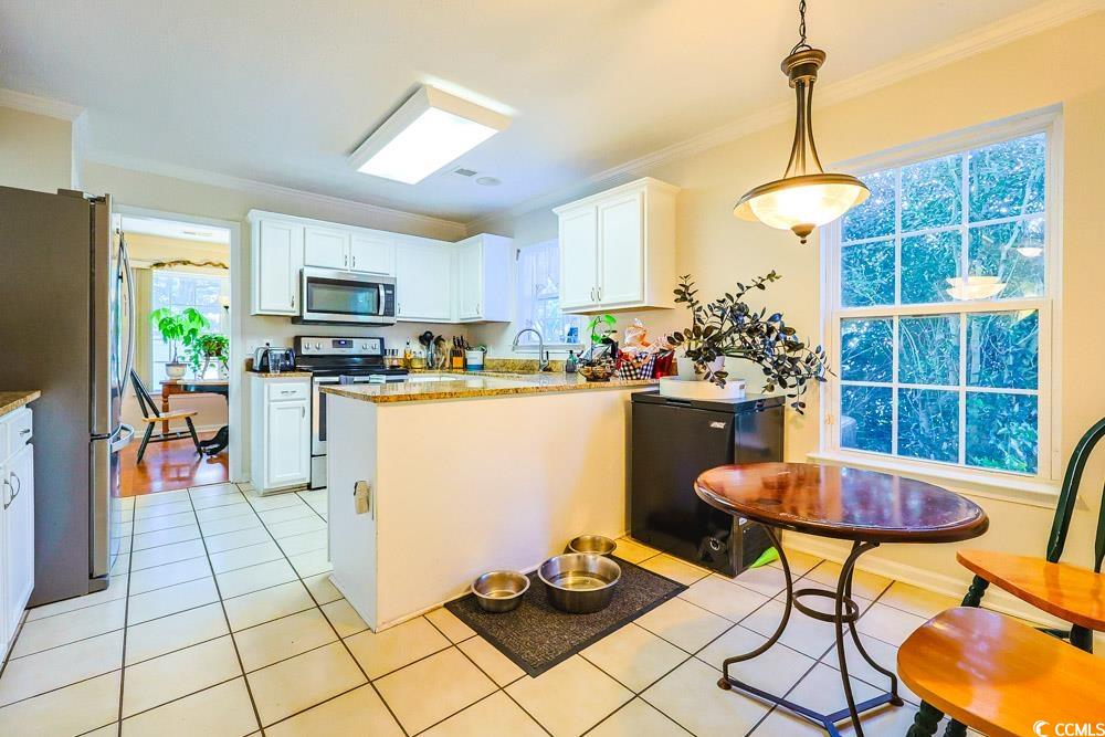 2033 Chadbury Lane Myrtle Beach, SC 29588 - Photo 5 of 39 Kitchen with white cabinets, appliances with stainless steel finishes, ornamental molding, light tile patterned floors, and pendant lighting