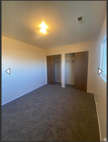 106 East Richelman Lane Wellington, UT 84542 - Photo 22 of 35 Unfurnished bedroom featuring two closets and dark colored carpet