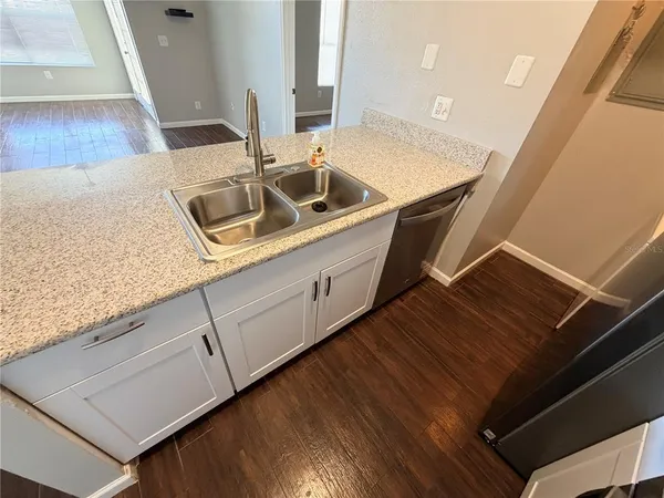 a kitchen with a sink and washing machine with wooden floor