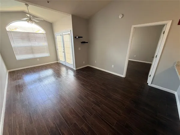 an empty room with wooden floor and windows