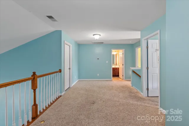 a view of a hallway with wooden floor and a bathroom