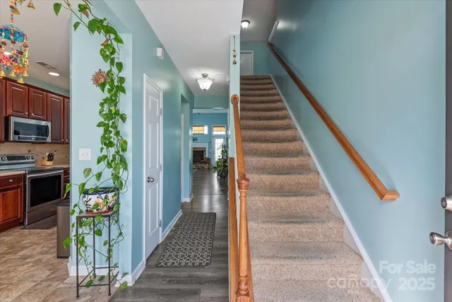a view of a hallway to a livingroom with wooden floor and stairs