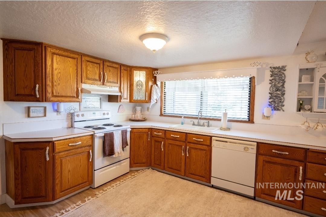 650 West 800 S Road Burley, ID 83318 - Photo 4 of 31 Kitchen with white appliances, wood finish cabinets, light countertops, a textured ceiling, and light wood-style floors