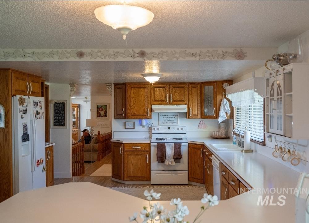 650 West 800 S Road Burley, ID 83318 - Photo 5 of 31 Kitchen with wood finish cabinetry, white appliances, light countertops, and a textured ceiling