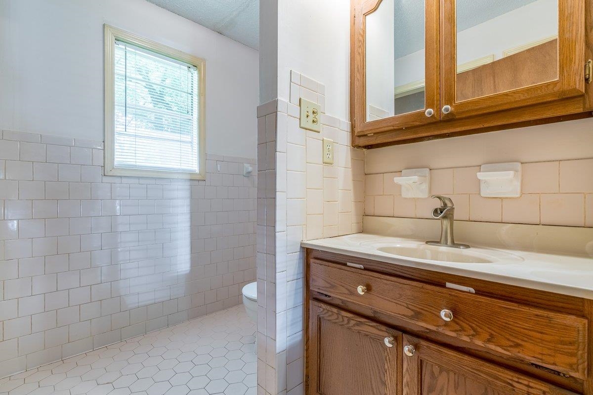 6237 Brunswick Road Arlington, TN 38002 - Photo 11 of 25 a bathroom with a granite countertop sink a toilet and a window