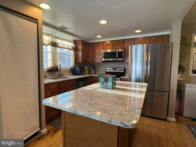 a kitchen with stainless steel appliances granite countertop a refrigerator a stove top oven a sink and dishwasher