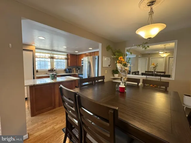 a kitchen with stainless steel appliances granite countertop a sink dishwasher and a dining table with wooden floor