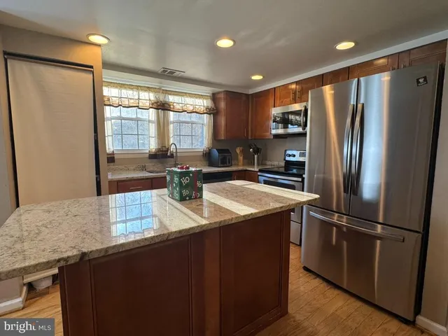 a kitchen with stainless steel appliances granite countertop a refrigerator a sink a stove and a refrigerator with wooden floor