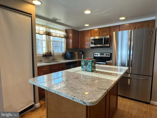 a kitchen with stainless steel appliances granite countertop a refrigerator a stove and a sink