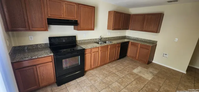 a kitchen with granite countertop a sink stove and cabinets