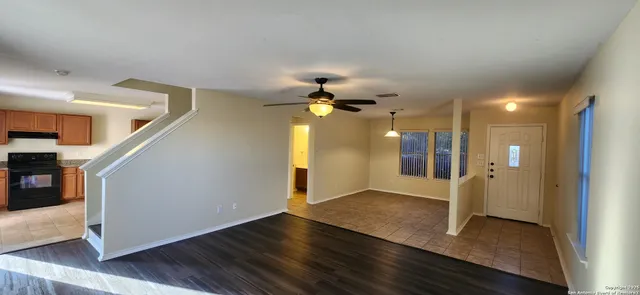 a view of empty room with wooden floor and fan