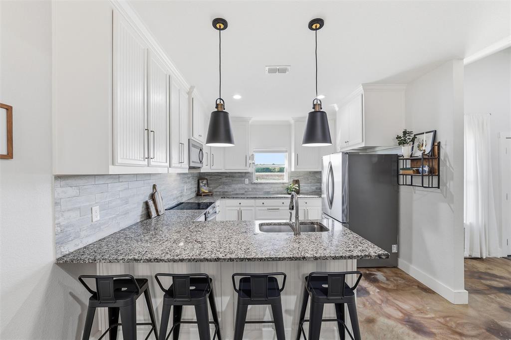 405 Advance Road Weatherford, TX 76088 - Photo 14 of 35 a kitchen with granite countertop kitchen island stainless steel appliances and wooden floor