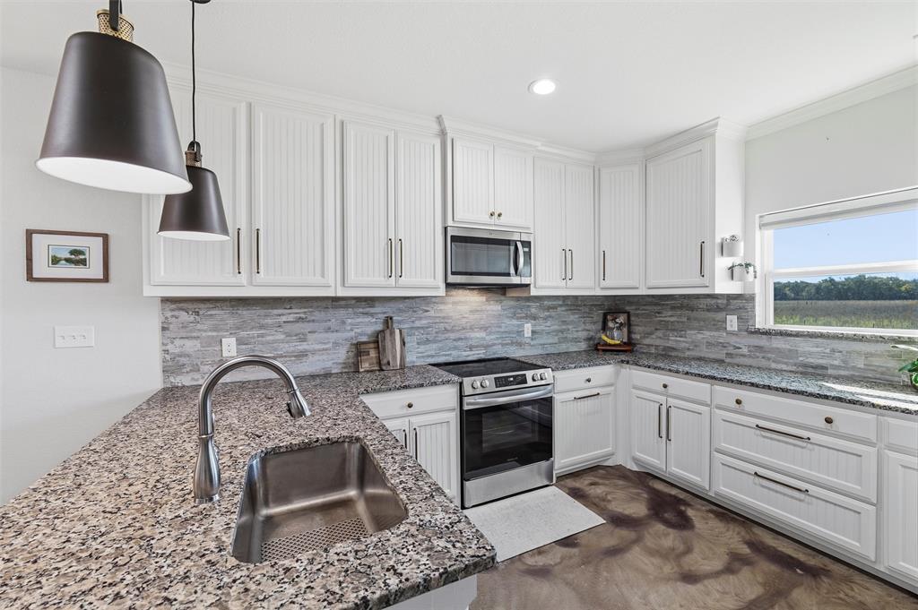 405 Advance Road Weatherford, TX 76088 - Photo 16 of 35 a kitchen with granite countertop a stove top oven a sink a dining table and chairs