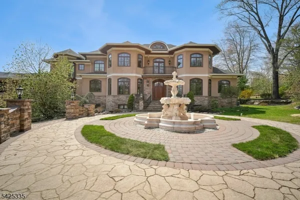 a front view of a house with garden and trees