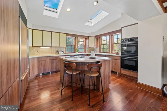 a kitchen with stainless steel appliances granite countertop a stove a refrigerator a sink a dining table and chairs with wooden floor