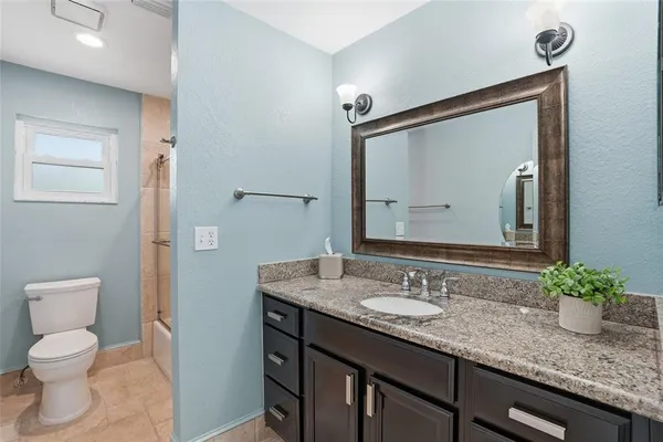 a bathroom with a granite countertop sink a toilet and a large mirror