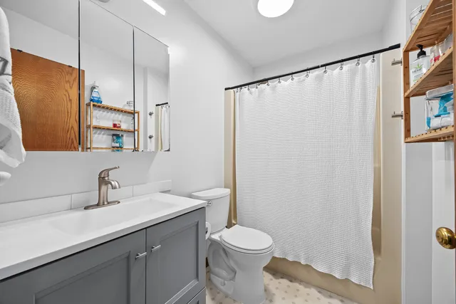 a bathroom with a sink a toilet a mirror and shower