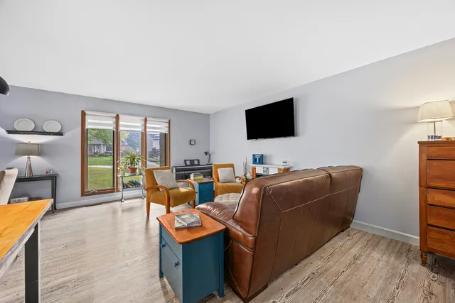 a living room with furniture a flat screen tv and floor to ceiling window