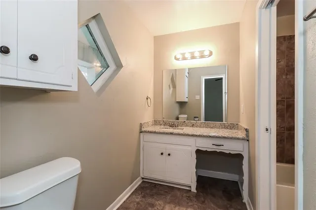 a bathroom with a granite countertop sink vanity mirror and toilet