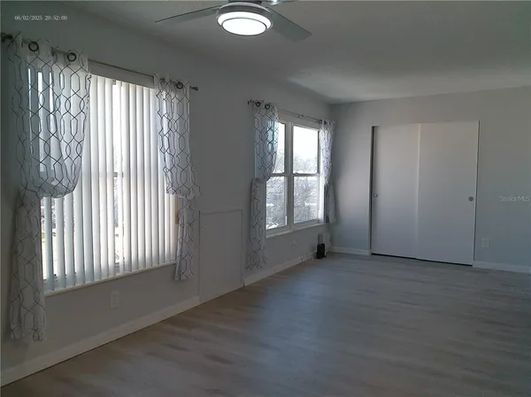 an empty room with wooden floor and windows