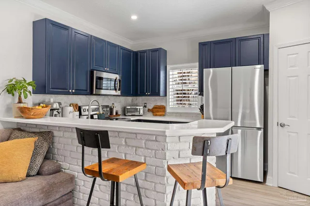 a kitchen with stainless steel appliances a table chairs refrigerator and microwave