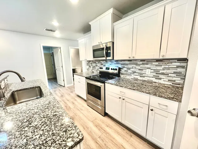 a kitchen with stainless steel appliances granite countertop a sink stove and cabinets