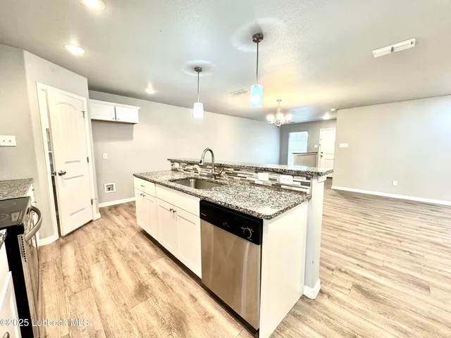 a large kitchen with kitchen island a stove a sink dishwasher and a oven with wooden floor