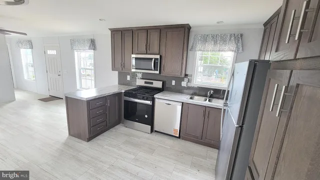 a kitchen with stainless steel appliances granite countertop a refrigerator a sink a stove a washer dryer and a refrigerator