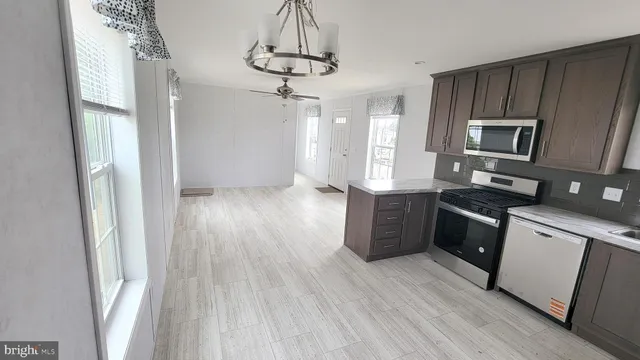 a kitchen with stainless steel appliances granite countertop a refrigerator a sink dishwasher a stove and white countertops with wooden floor