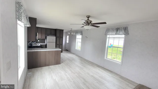 a kitchen with stainless steel appliances granite countertop a refrigerator a sink dishwasher a stove and a dining table with wooden floor