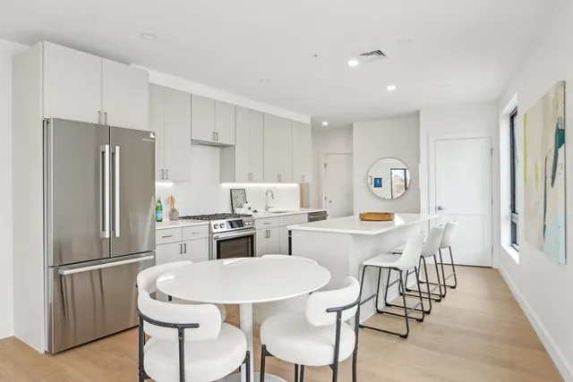 a kitchen with stainless steel appliances a dining table chairs and refrigerator
