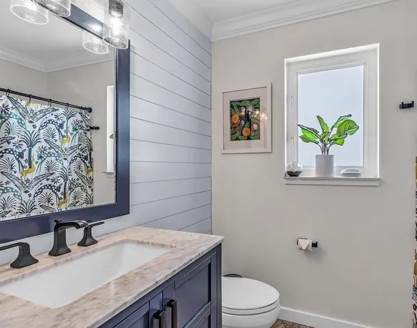 a bathroom with a granite countertop sink a toilet and mirror