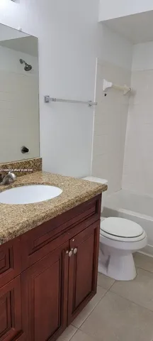 a bathroom with a granite countertop toilet sink and mirror